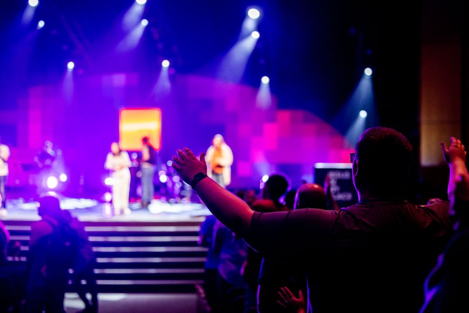 Excited concert audience under colorful stage lighting during performance.